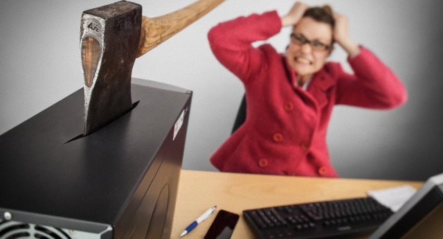 Frustrated office worker with axe embedded in desktop computer | 早安健康新訊平台